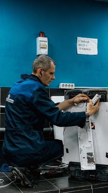 A technician examining and troubleshooting a piece of gardening equipment indoors, kneeling on a dark tiled floor in front of a blue wall. The technician is dressed in a navy blue work uniform with a 